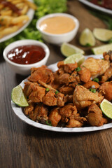 Portion of fried chicken with lemon. Lettuce, green onion, ketchup and mayonnaise