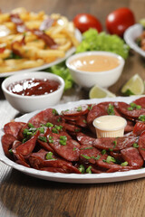 Portion of pepperoni sausage with lemon. Lettuce, green onion, ketchup and mayonnaise