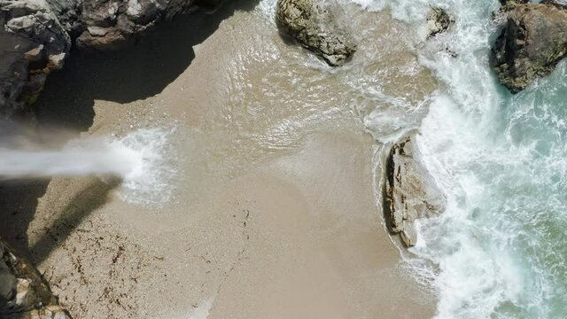 Close up scenic falls in beautiful Big Sur park, California USA. Overhead world famous waterfall landmark. Cinematic clear green water and sandy beach. Nature wilderness, vertical mobile content 9:16