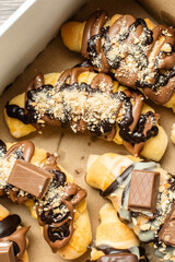 Top view on baked sweet croissants in box with chocolate biscuit and cream