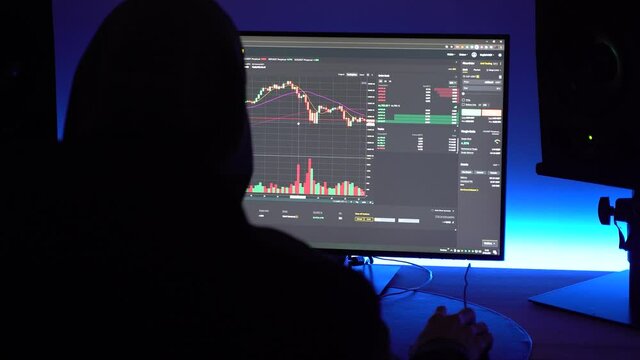 A trader with hoodie looking at financial chart trading bitcoin and cryptocurrency on PC