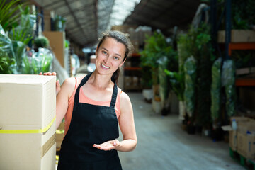 Portrait of friendly female garden store worker posing at shopping room