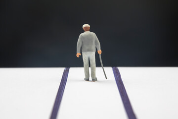 miniature people. an elderly pensioner with a stick walks the road until the end of his life. loneliness and depression
