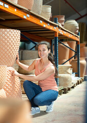 Young woman customer holding big decorative clay pot for garden in the shop