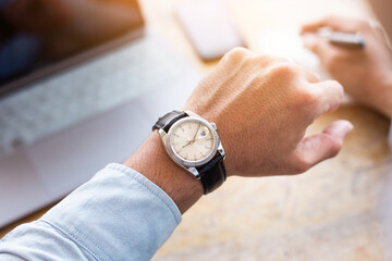 looking at luxury watch on hand check the time writing business information in notepad at...