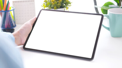 Close up of man hand holding digital tablet with blak screen on working table background for mock up, template