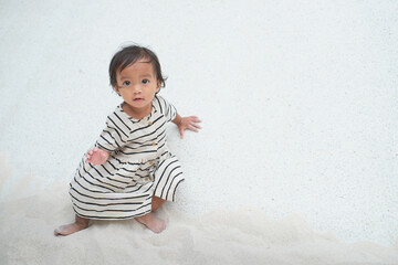 Cute Asian toddler baby girl child playing with sand in sandbox at public playground, Fine motor skills development for little kid with copy space for text