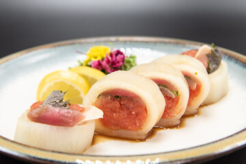 Rings of albacore fish filled with spicy tuna sushi with beautiful presentation on a plate garnished topped with a flower.