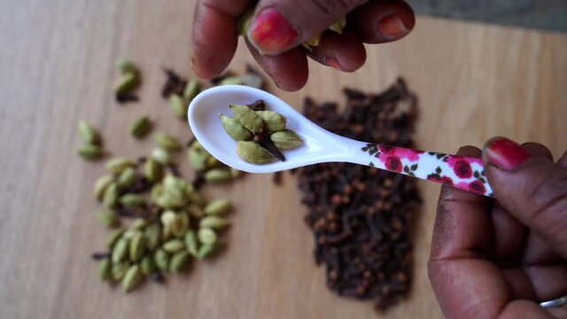Female Hand is picking green cardamom pods on a wooden background. Dry cloves, cardamoms and spicy spices. Slow motion video