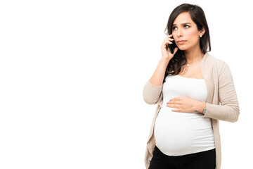 Pregnant woman looking scared while talking on the phone