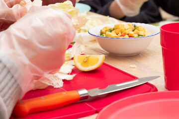 children in a school class at a labor lesson prepare a vegetable salad. parts of hands close-up. selective focus
