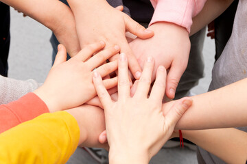 many different children's hands and the teacher's hand are held together while playing at school during recess