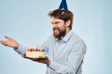 Man with a plate of cake and a festive candle blue background cap corporate party