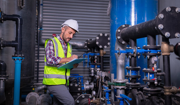 Industry engineer worker wearing safety uniform under checking the industry cooling tower air conditioner is water cooling tower air chiller HVAC of large industrial building to control air system.