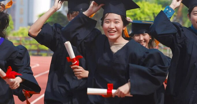 happy graduation students  holding diploma and running on the stadium at school