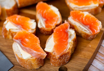 Sandwiches with butter and salted salmon on wooden board. Tasty seafood appetizer