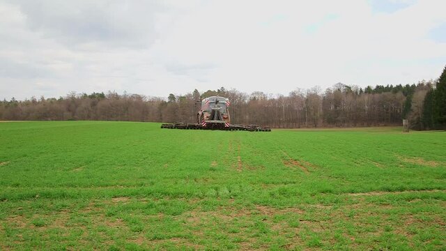 A big fertilizer tractor on the field moving away from the camera.