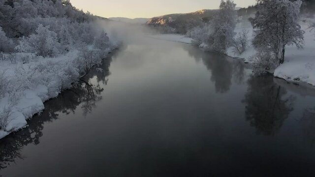 Winter wonderland in Norway. Drone footage of  a river and a gog over it   in very cold weather.