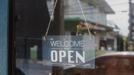 Welcome we're open vintage black and white retro sign on a coffee glass door cafe after coronavirus lockdown quarantine. Owner small business, food and drink, business reopen again concept.