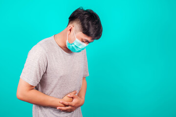 Asian man wear a T-shirt suffering from stomach ache because he has diarrhea on green background