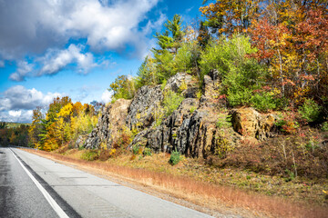Fototapeta na wymiar Highway with scenic autumn maple trees on the rocks along the road in Vermont