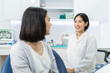 Asian dentist giving advice to patient girl about oral care treatment.