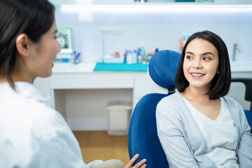 Caucasian girl consulting Asian female dentist about oral care checkup