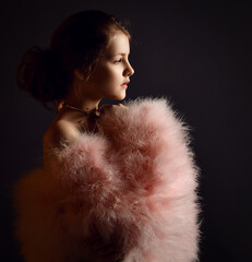 Portrait of gentle little kid girl, teen countess lady in furry clothes with big sleeves and bared shoulders looking hopefully into the distance over dark background. Side view - obrazy, fototapety, plakaty