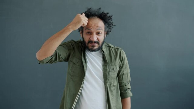 Slow motion portrait of mixed race guy knocking on head warning of stupid decisions looking at camera with disagreement and disapproval. People and attitude concept.