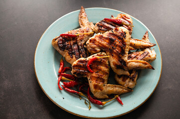 grilled wings on green plate and dark background, restaurant serving