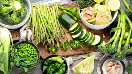 Set of various green raw healthy vegetables on wooden board
