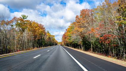 Straight flat highway lined with autumnal scenic maple trees in Massachusetts