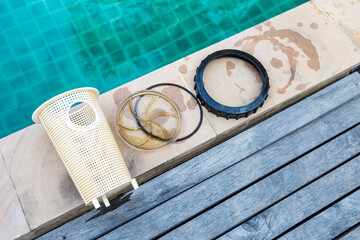 Swimming pool pump basket with lid and seal ring on swimming pool edge, pool maintenance and...