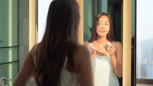 Young Asian girl with cleanser bottle and cotton pad remove cosmetic from face