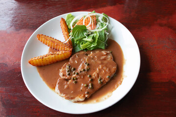 pork chop steak on white plate with french fries and salad