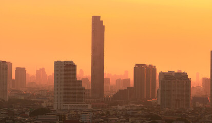 Fototapeta na wymiar Air pollution. Smog and fine dust of pm2.5 covered city in the morning with orange sunrise sky. Cityscape with polluted air. Dirty environment. Urban toxic dust. Unhealthy air. Urban unhealthy living.
