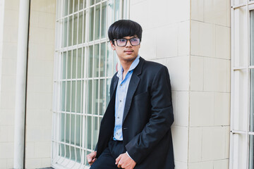 Handsome young asian wearing black suit and glasses posing in front of the camera