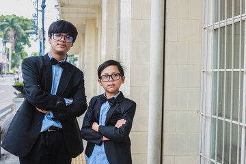 Fototapeta premium Two brothers with vintage office look, wearing glasses, black ribbon and black suit posing in front of the camera while crossed arm