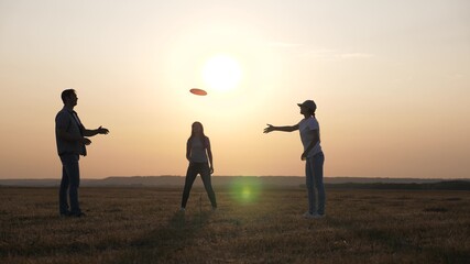 Fototapeta na wymiar Children and Parents, Family play in field. Happy family, dad, mom and daughter are playing, throwing flying red disc to each other in park. Carefree young people have fun together. Sports and youth.