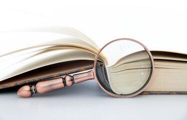 The opened book, the magnifying glass on the book and the coins observed in the magnifying glass