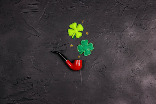 Smoking pipe with decorative clover leave on black background. Saint Patrick's Day concept.