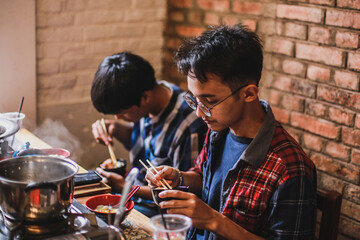 Two asian man eating together at the barbecue party. Food, people and family time concept.