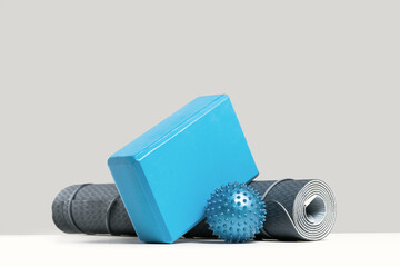 Rolled blue yoga mat and foam block or brick, massage ball. Gender neutral fitness and exercise...