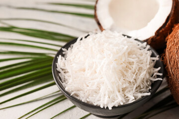 Bowl with coconut flakes on light background