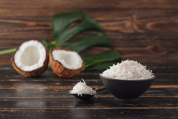 Bowl with coconut flakes on wooden background