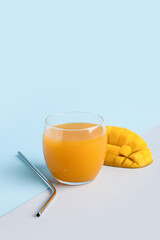 Glass of fresh mango juice on color background