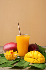 Glass of tasty juice and fresh mango on color background