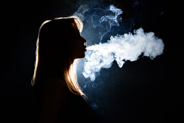Silhouette of smoking young woman on dark background