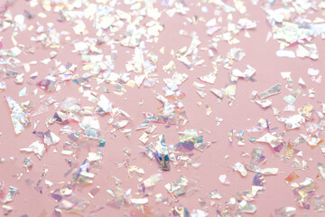 neon pearl foil confetti on light pink background. Festive, party or holiday glowing backdrop. Flat lay, top view.