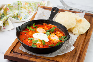 shakshuka - scrambled eggs with herbs, beans and tomatoes in a skillet with lean crispbread